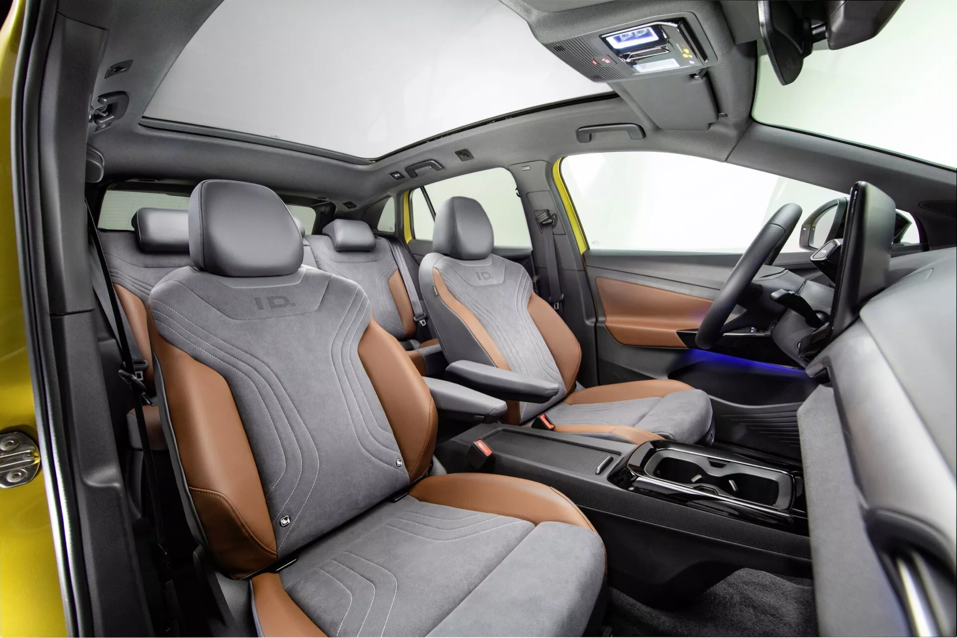 Wnętrze VW ID.4 1. generacji 2020 z perspektywy pasażera przedniego, pokazujące przednie siedzenia w dwóch kolorach, elegancką konsolę środkową, system infotainment z ekranem dotykowym i panoramiczny dach, podkreślające nowoczesny i premium design z minimalistycznymi funkcjami technologicznymi