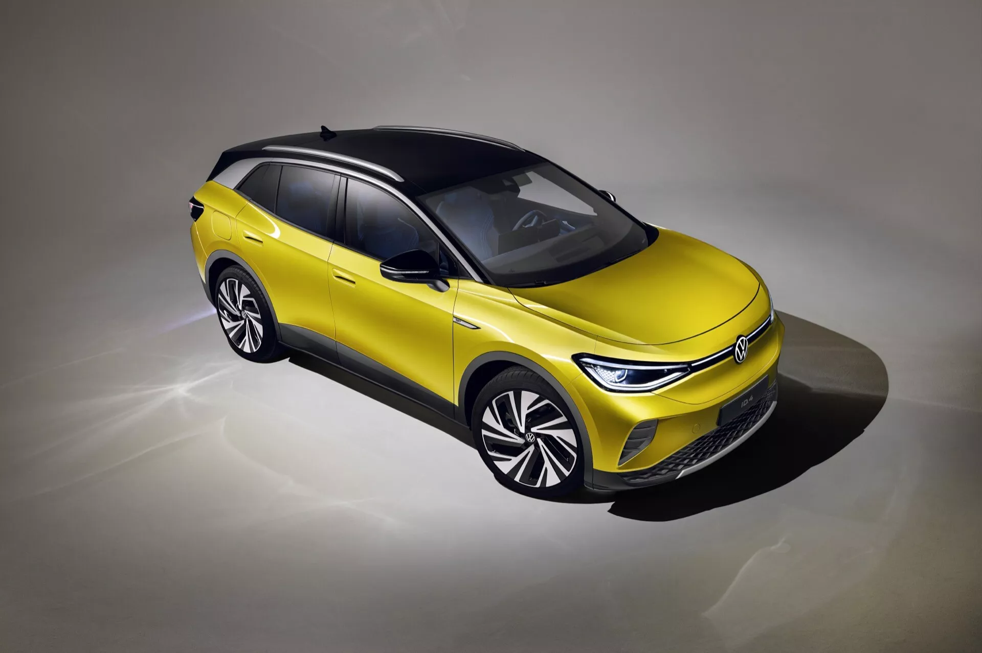 Volkswagen ID.4 1. generacji 2020 prezentuje nowoczesny design z dwukolorowym malowaniem, zaawansowanymi reflektorami LED i aerodynamicznymi kołami wielowiązkowymi z wysokiej perspektywy trzy czwarte, podkreślając ekologiczne funkcje pojazdu elektrycznego i opcje luksusowe jak panoramiczny dach