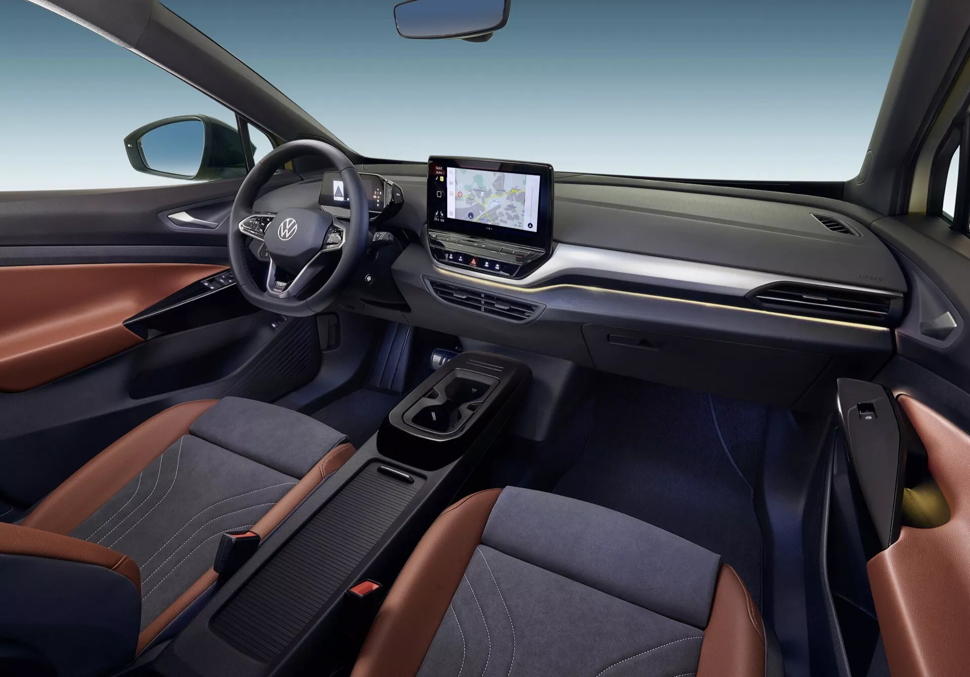 Wnętrze VW ID.4 z 2020 roku pokazujące przednią kabinę z perspektywy pasażera, z kierownicą po lewej stronie, logiem Toyota, ekranem dotykowym systemu infotainment, kontrolą klimatyzacji i dwukolorowymi tapicerowanymi siedzeniami