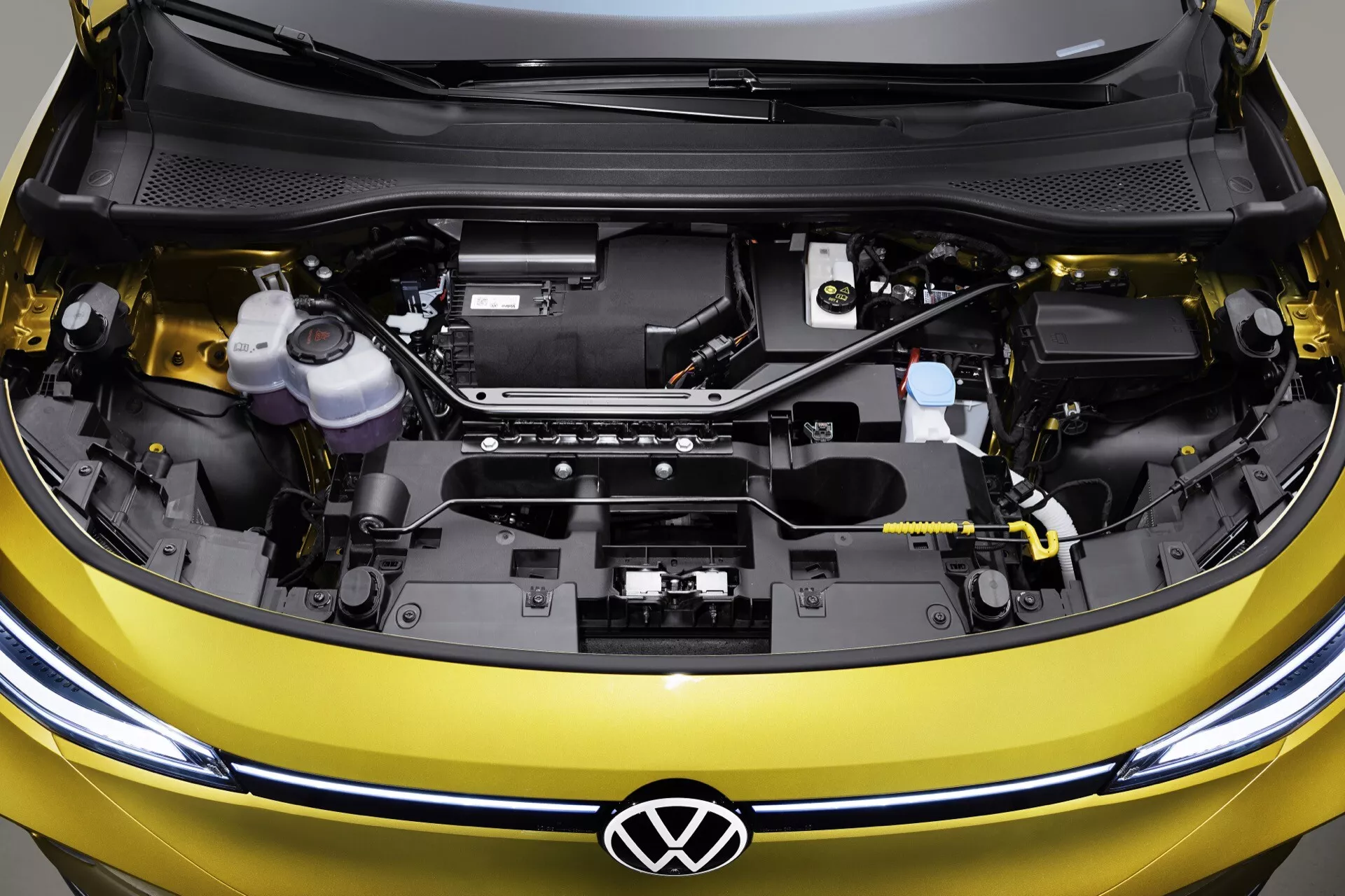 Zdjęcie z góry i z bliska otwartej komory silnika VW ID.4 2020 (1. generacja), pokazujące czysty i zorganizowany układ z logo Volkswagen i elementami silnika