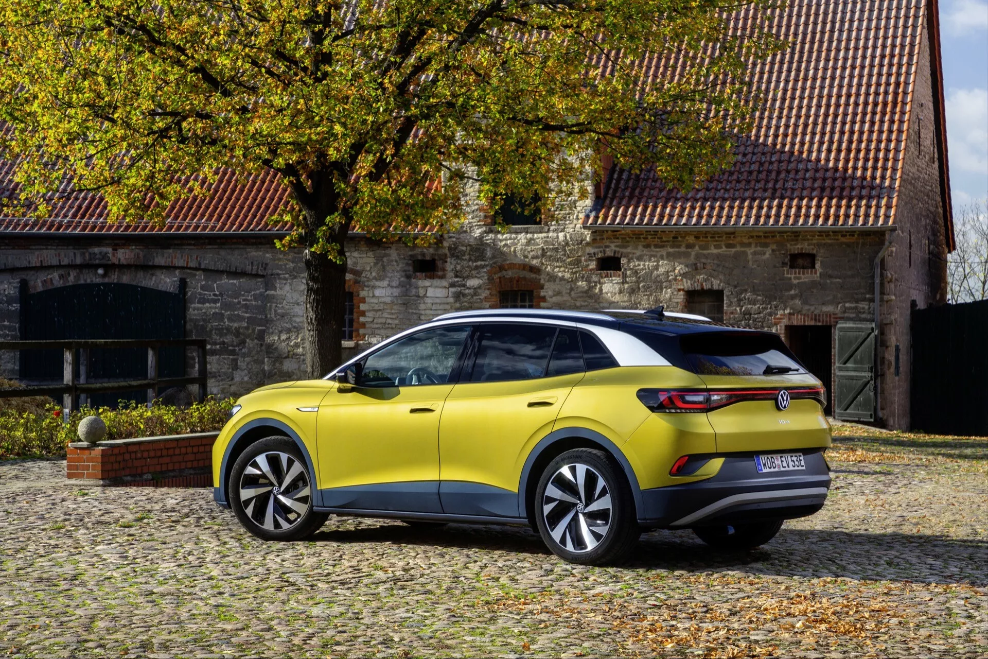 Widok z tyłu pod kątem trzech czwartych na limonkowo-żółte SUV crossover VW ID.4 1. generacji z 2020 roku zaparkowane na zewnątrz, pokazujący profil boczny, tył, aerodynamiczny design, tylne światła LED i wieloramienne felgi aluminiowe