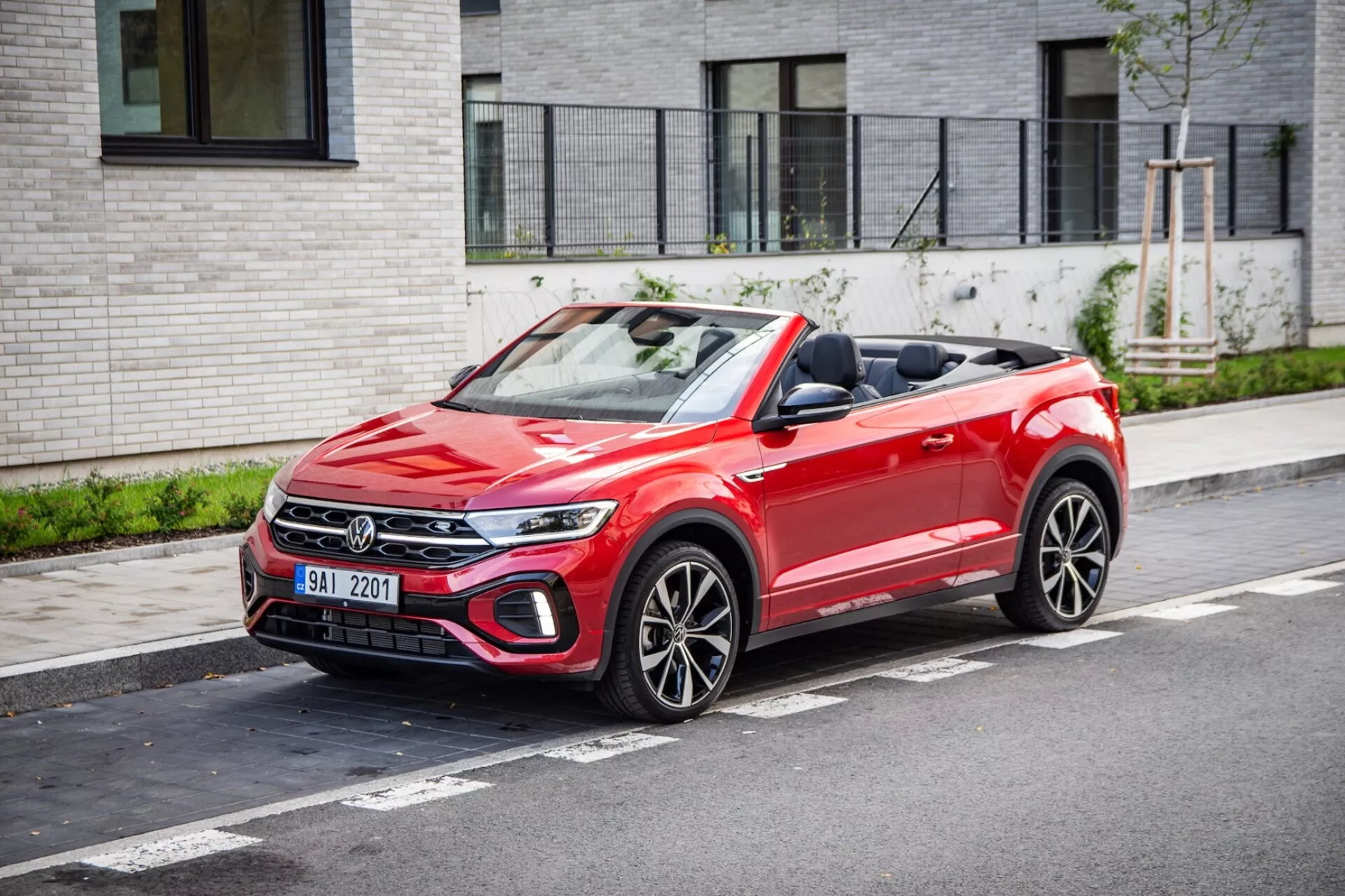 VW T-Roc Cabriolet 2022 zaparkowany na miejskiej ulicy, pokazujący przedni grill, reflektory LED, złożony materiałowy dach kabrioletu oraz sportowe felgi wieloramienne