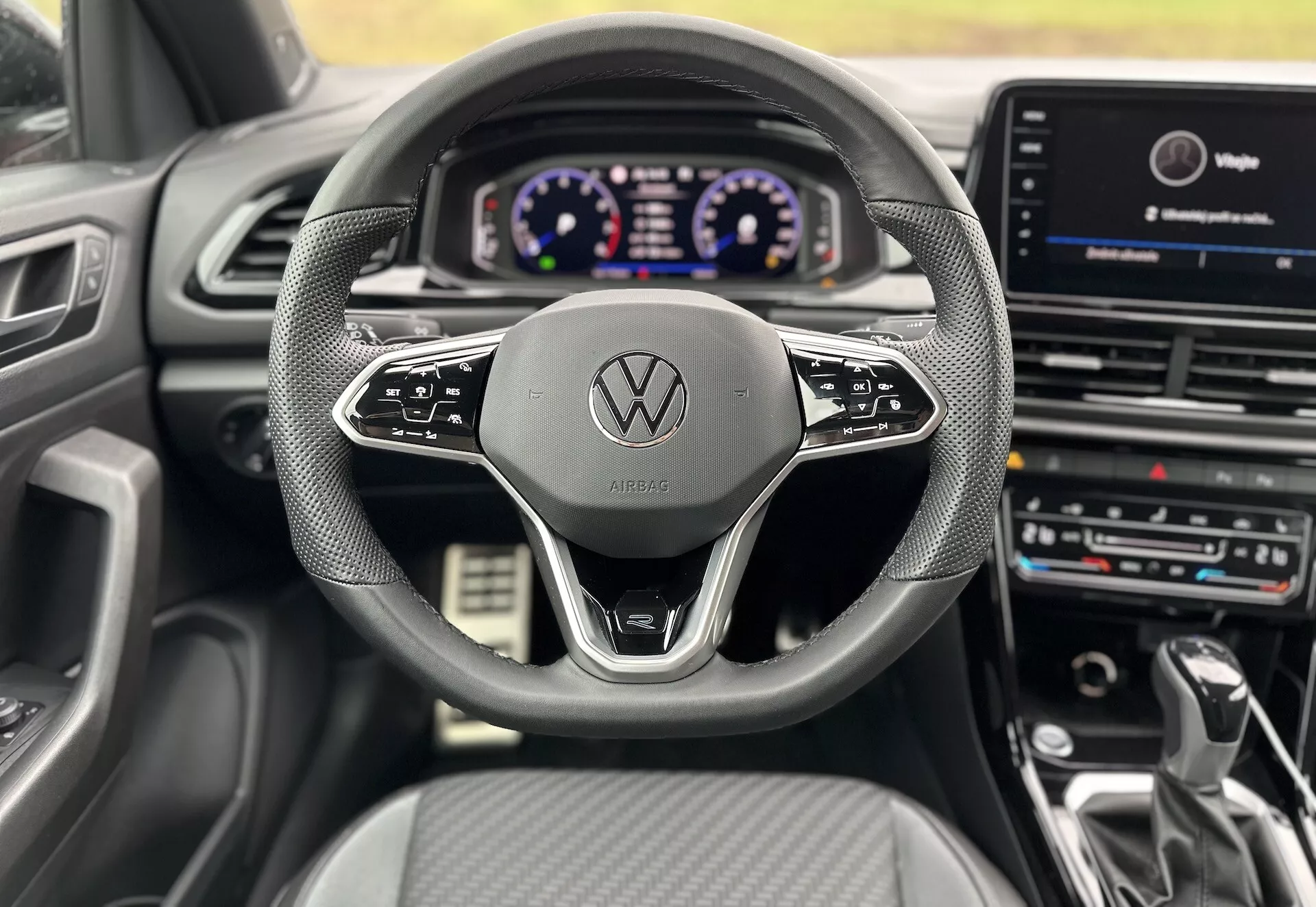 Widok wnętrza z miejsca kierowcy Volkswagen T-Roc Cabriolet 2022, pokazujący kierownicę, cyfrowy panel instrumentów i centralny system rozrywki