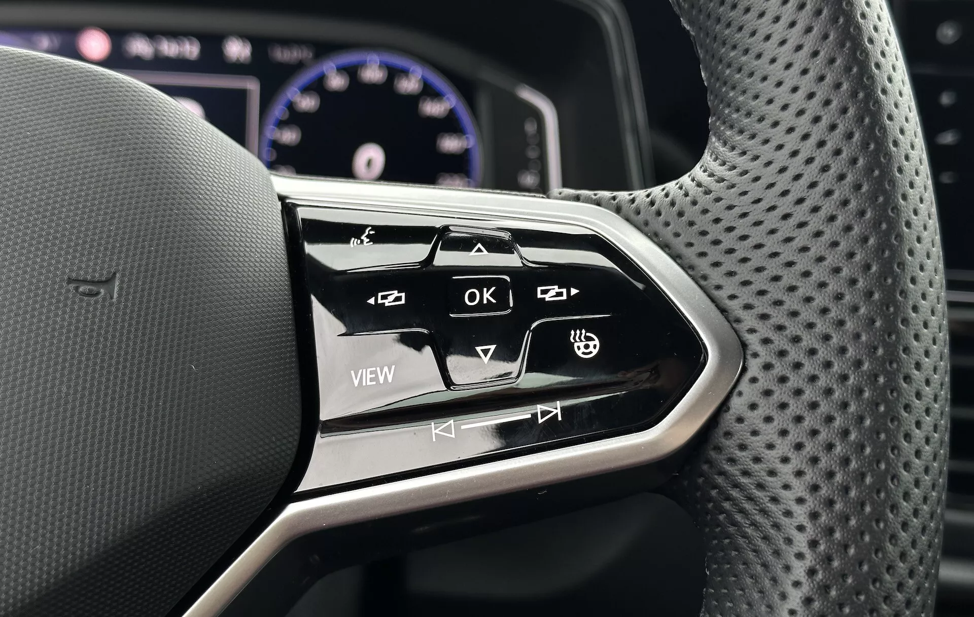 Zbliżenie na wielofunkcyjne przyciski kierownicy w VW T-Roc Cabriolet 2022, pokazujące ergonomiczny design i interaktywne przyciski do systemu infotainment i ustawień pojazdu