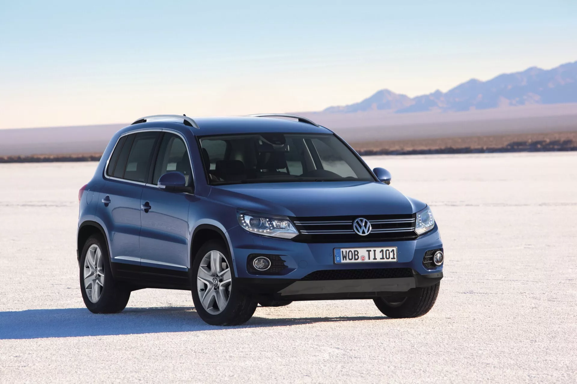 SUV Volkswagen Tiguan z 2007 roku na suchej solance, prezentujący swój dynamiczny trzykwartalny widok frontowy z reflektorami projekcyjnymi, światłami przeciwmgielnymi, alufelgami wieloramienne, kierunkowskazami zintegrowanymi w lusterkach bocznych, relingami dachowymi i panoramicznym dachem przy naturalnym oświetleniu