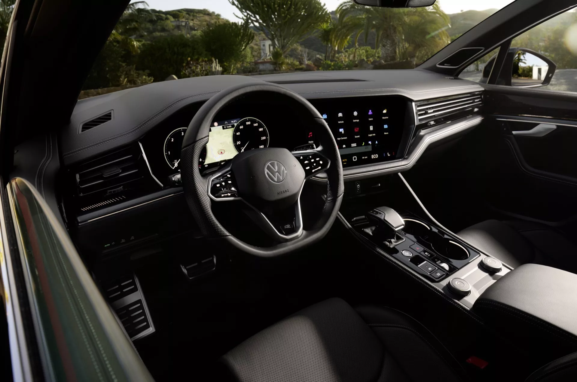 Widok wnętrza VW Touareg 2023 z tylnego siedzenia, wyposażony w cyfrową deskę rozdzielczą i system infotainment z ekranem dotykowym